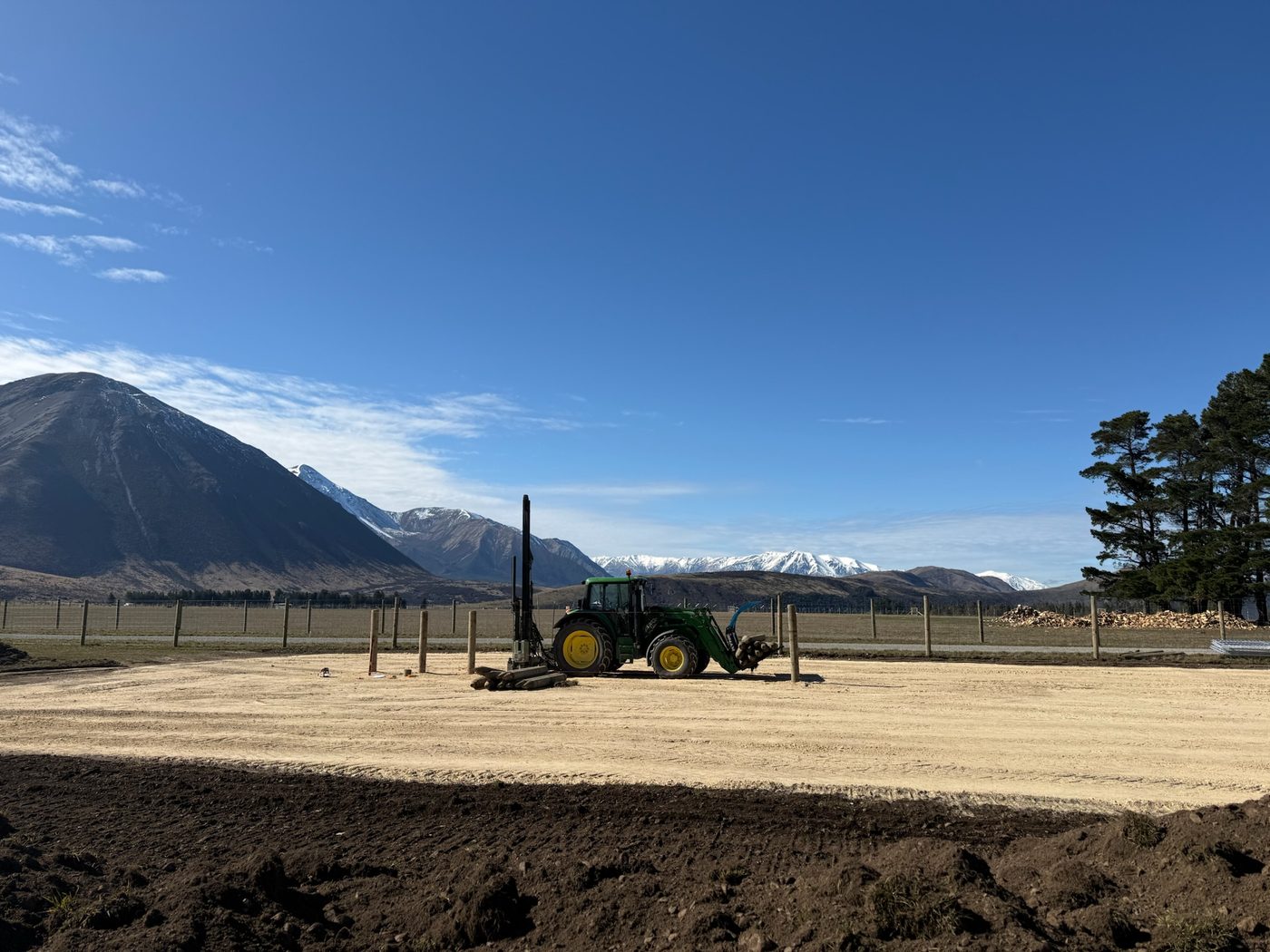 Post driver rig working a building pad with Southern Alps in the background