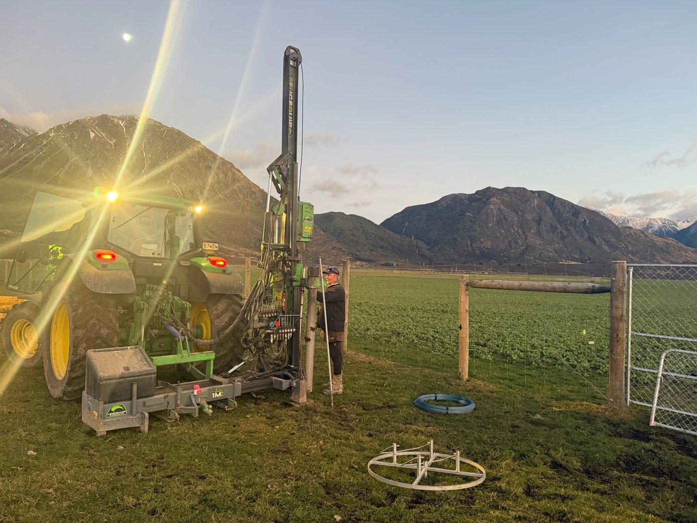 Mark driving a strainer post at golden hour, Canterbury paddock